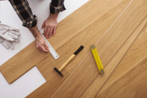 A man measuring wood flooring for installation.