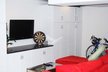 A basement entertainment space with a couch, built-in storage, and TV stand.