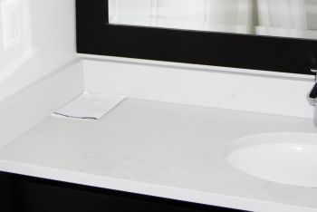 A close-up image of a white bathroom countertop and a dark vanity mirror.