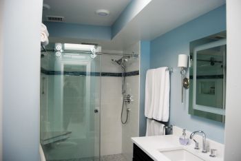 Bathroom with blue walls, dark cabinets, and a frameless glass shower.