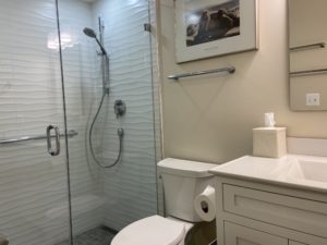 Bathroom with a white wooden sink stand and a frameless glass shower.