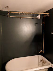 A white clawfoot bathtub with gold hardware.