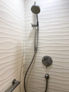 A close-up of white wave-textured tile in a shower.