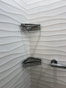 Built-in storage racks in a shower with wavy-textured walls.
