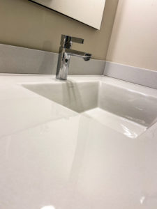 A close-up of a white stone sink with stainless steel hardware.
