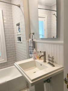 A white porcelain sink in a bathroom with a tiled tub.