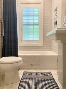 A bathroom with a gray-tiled shower and tub.