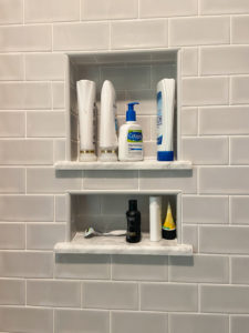 Built-in storage for toiletries in a tile shower.