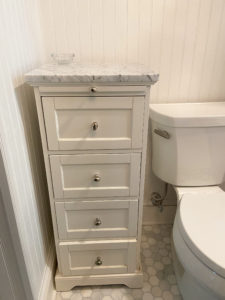Small bathroom cabinet next to new toilet.