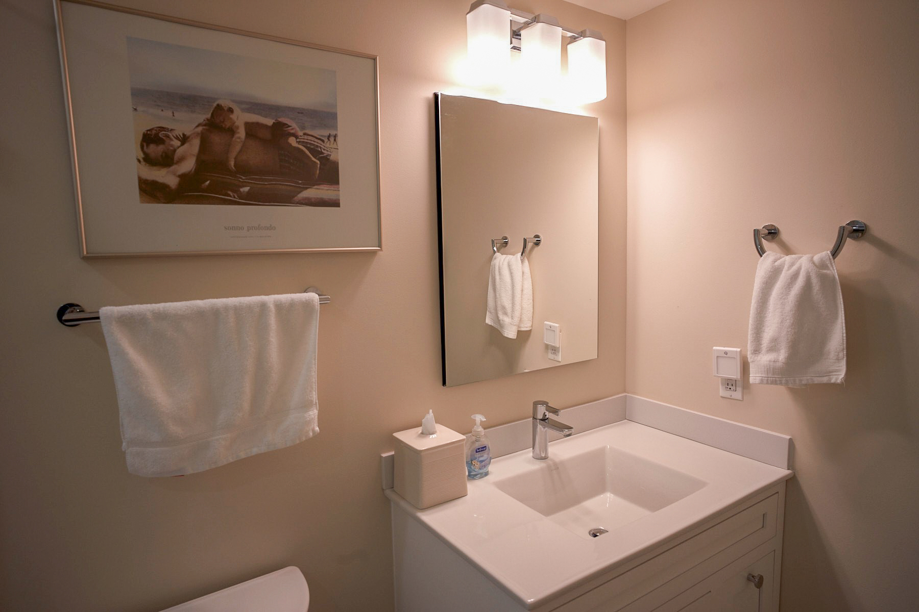 Bathroom with off-white walls, white countertops, and silver hardware.