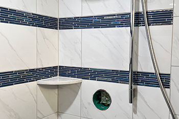 A shower with white marble and blue subway tile accents.