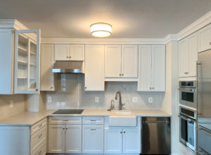 Small renovated kitchen with white cabinets, farmhouse sink, and updated appliances.