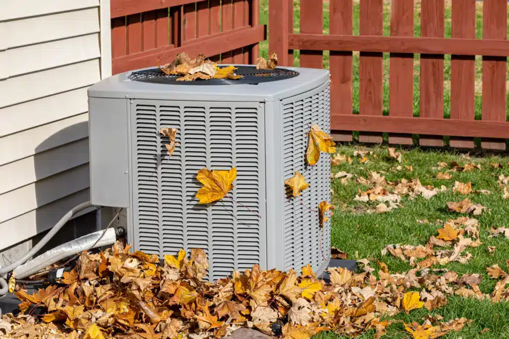 Outdoor HVAC unit covered in autumn leaves