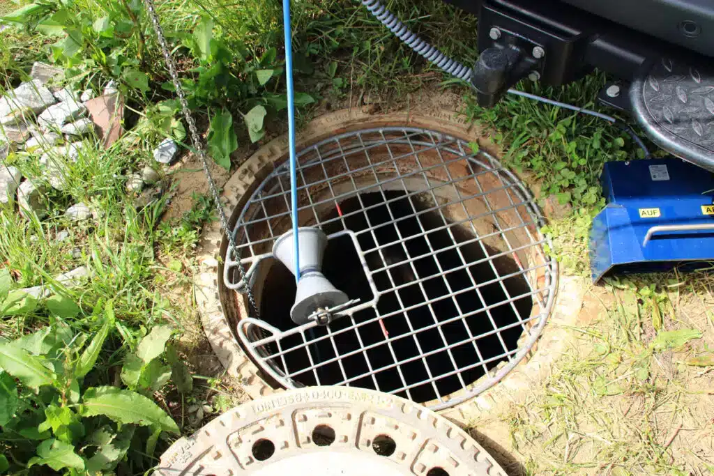 A round sewer entrance with a camera being lowered iin