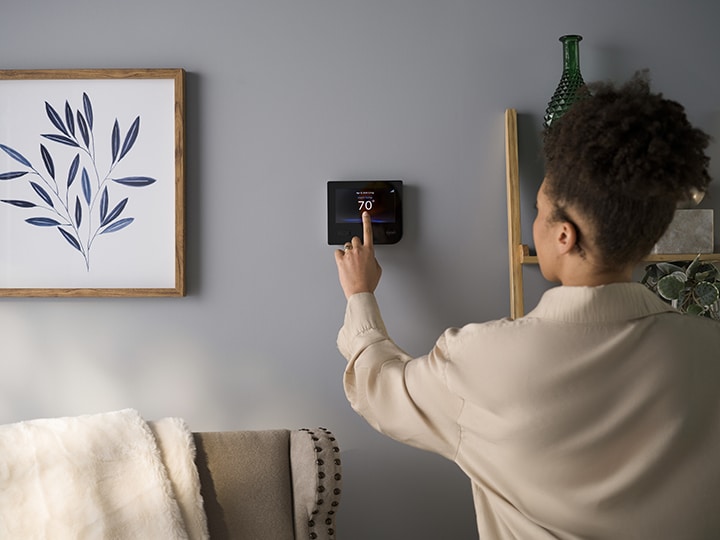 homeowner turning on smart thermostat fall